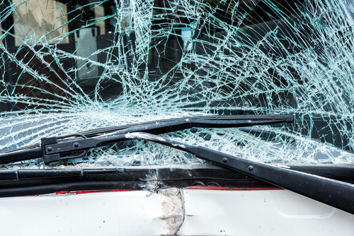 Close-up of a shattered bus windshield with visible cracks spreading across the glass after a collision.