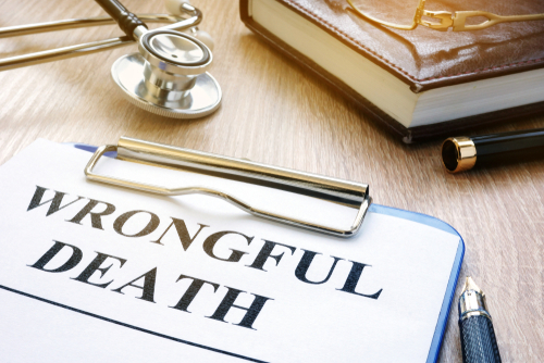 Clipboard with a document labeled “Wrongful Death,” stethoscope, and legal book on a wooden desk.