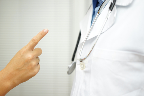 Person pointing a finger at a doctor wearing a stethoscope.