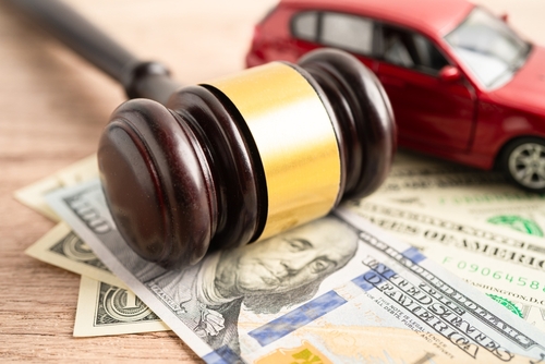 A judge’s gavel resting on cash beside a toy car, symbolizing compensation and legal claims after a Renton car accident.