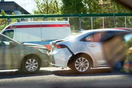 Two vehicles involved in a rear-end collision in Renton with an ambulance in the background, representing a typical Renton car accident scene.