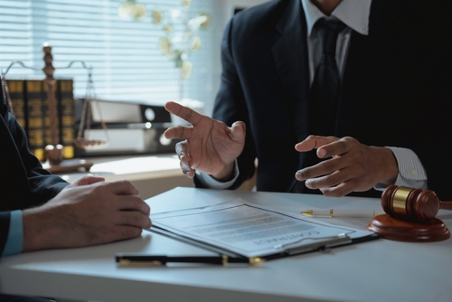 A Kent personal injury lawyer speaking with a client across a desk covered with legal documents, a gavel, and scales of justice.