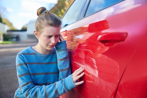 Abogado de accidentes automovilísticos en Seattle ayudando a adolescente tras un choque con daños visibles en el automóvil.
